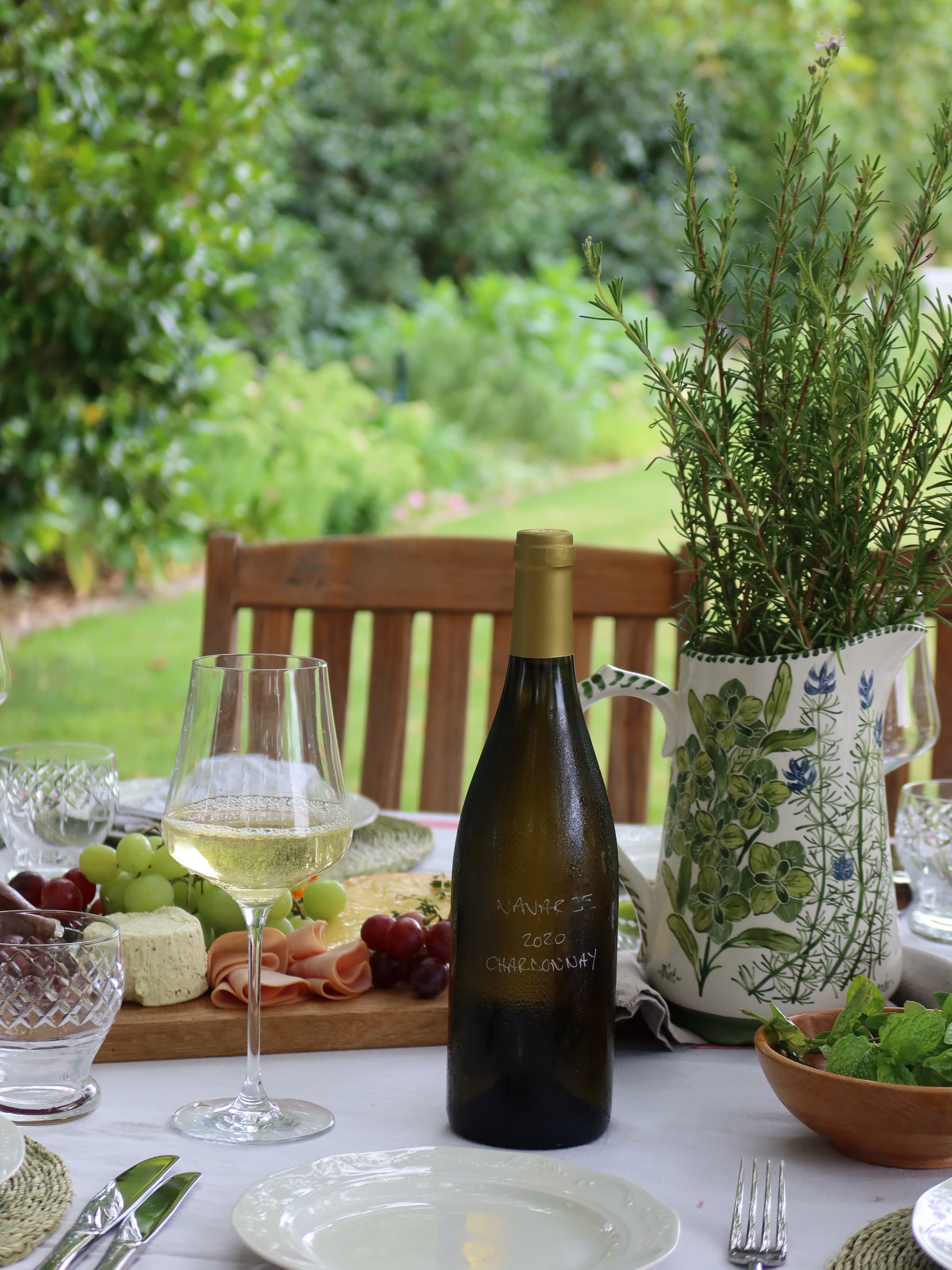 Outdoor table with Navarre Chardonnay, cheese board, and rosemary