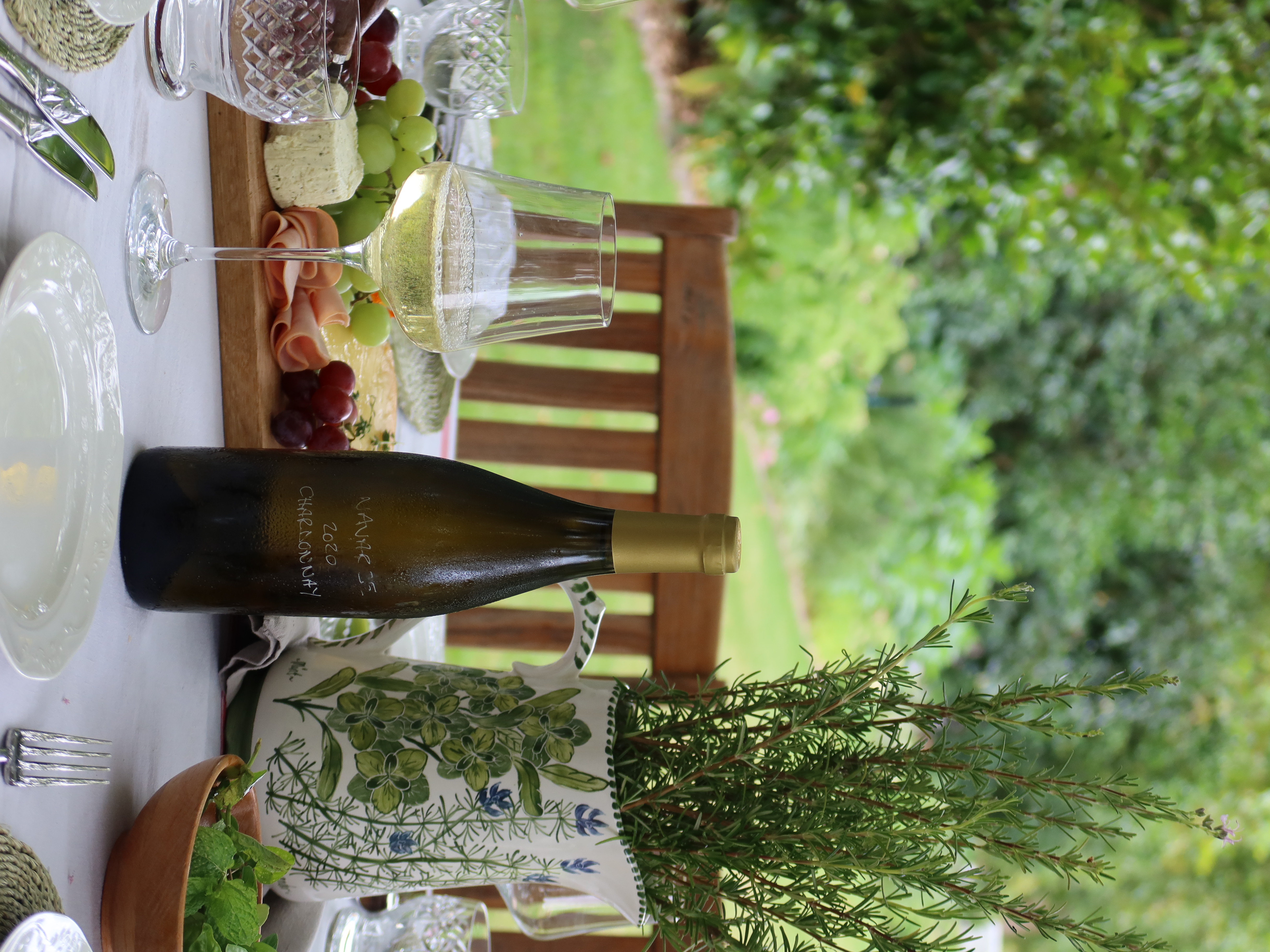Outdoor table with Navarre Chardonnay, cheese board, and rosemary
